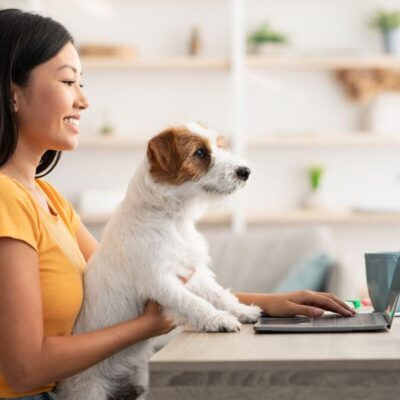 Kobieta z psem przegląda sklep zoologiczny online na laptopie.